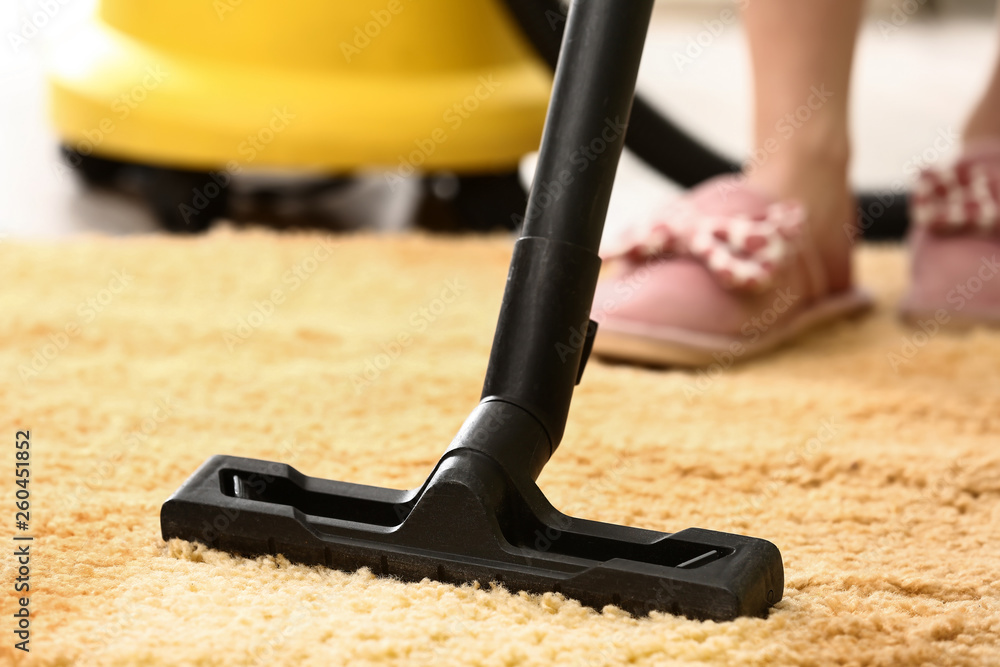 Woman cleaning carpet with hoover at home