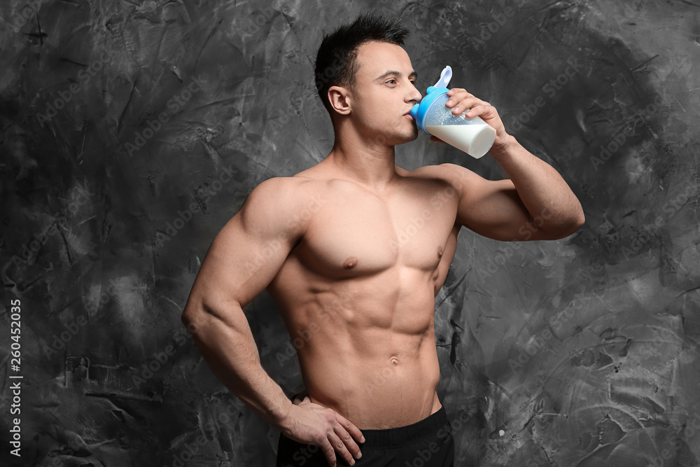 Sporty man drinking protein shake on grunge background