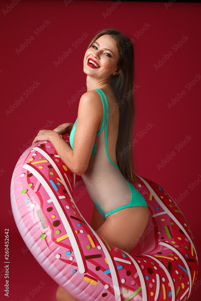 Beautiful young woman with inflatable ring on color background