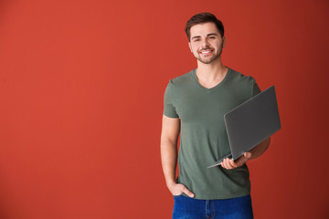 Male programmer with laptop on color background
