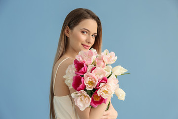 Poster - Young woman with bouquet of beautiful tulips on color background