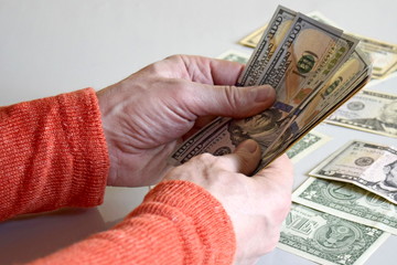 Caucasian man's hands counting dollar banknotes on gray surface. Male holding money currency of United States on gray background. Close-up. Selective focus.