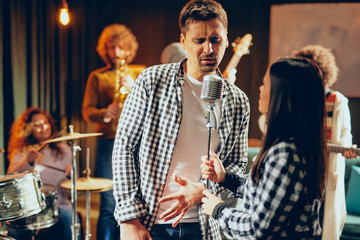 Sticker - Singers practicing for duet. In background band playing. Home studio interior.