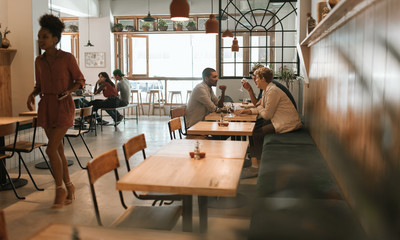 Friends talking together over drinks and lunch in a bistro