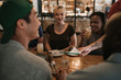 © mavoimages - Waiter handing the bill to smiling customers in a bar