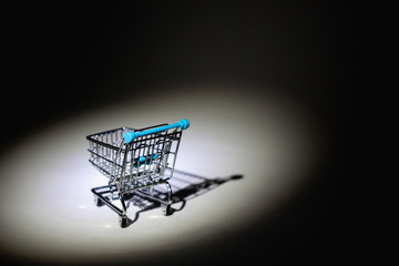 Spotlight and shopping trolley in the dark room.