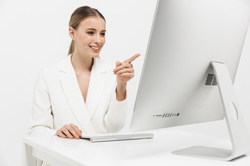 Wall Mural - Beautiful amazing woman sitting isolated over white wall background using pc computer.