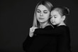 A portrait of beautiful pregnant mother with her little daughterirl dressed in black tights against dark background.