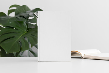 Poster - White book mockup with workspace accessories and a monstera plant.