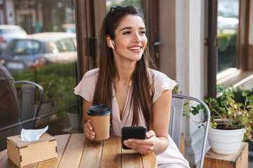 Poster - Smiling pretty woman sitting at the cafe outdoors