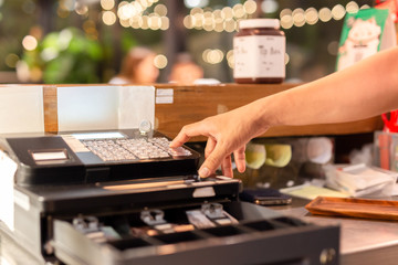 Shot in low light hand pressing electronic cash register in a shop.