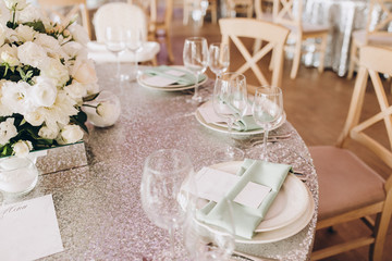 on the banquet table are plates, cutlery, glasses and flower arrangements