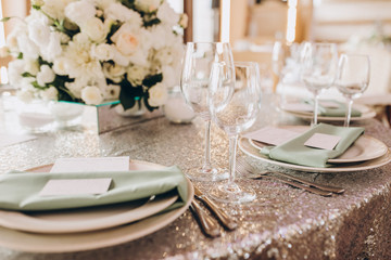 on the banquet table are plates, cutlery, glasses and flower arrangements