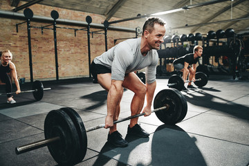 Wall Mural - Fit man smiling during a gym weightlifting class