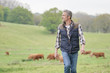 © goodluz - Farmer walking in field with cattle in the background