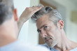 © goodluz - Portrait of mature handsome man looking in mirror at home