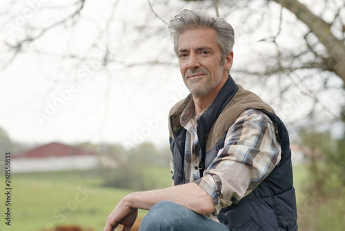 Fotografía Attractive farmer leaning on fence looking at camera