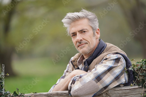 Cuadros en Lienzo Attractive farmer leaning on fence looking at camera