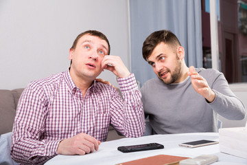 Wall Mural - Friend soothing upset man at home table