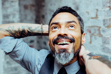 Wall Mural - Portrait of a smiling mature man with tattoos looking up