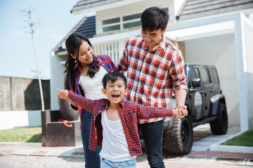 young asian family with kid in front of their house and car