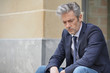 © goodluz - Unhappy businessman sitting outdoors