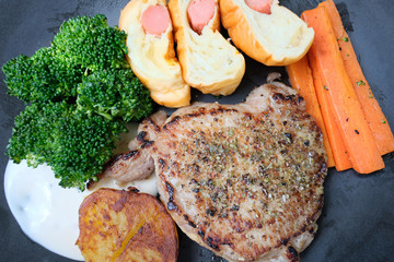 Meat steak with grilled vegetables and spices placed in a plate on a wooden table