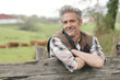 © goodluz - Attractive farmer leaning on fence looking at camera