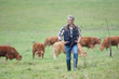 © goodluz - Farmer walking in field with cattle in the background