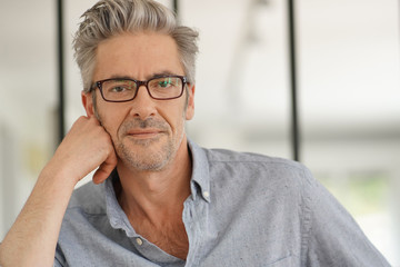 Wall Mural - Portrait of handsome mature man wearing glasses smiling at camera