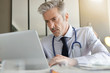 © goodluz - Mature doctor working in contemporary clinic office
