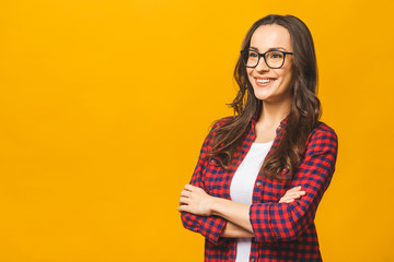 Wall Mural - Portrait of a pretty smiling woman in casual and glasses posing isolated on a yellow background.