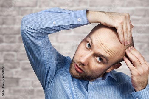 Portrait Of A Bald Man Looking At His Balding Head With A