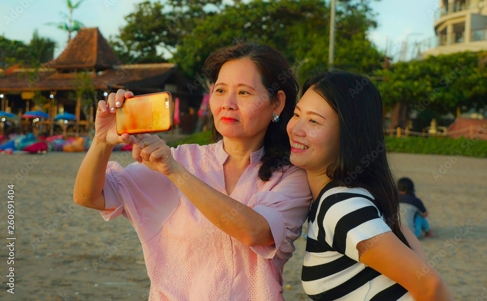 young happy and pretty Asian Chinese girl on the beach taking selfie ...