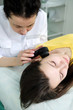 © skvalval - Female dermatologist using a professional dermatoscope while doing skin examination, Checking benign moles on face. Dermatologist examining birthmarks and moles on a female patient. Dermatology Clinic