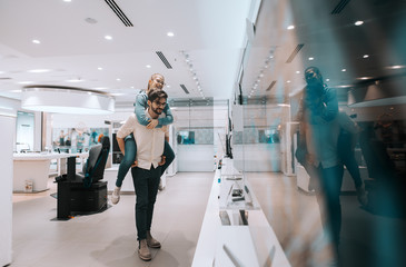 Wall Mural - Multicultural attractive couple having piggyback at tech store.