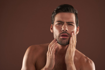 Wall Mural - Young man focused on touching his bristle cheek