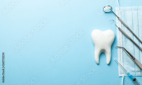 Obraz Dibond Ząb i stomatologiczni instrumenty na błękitnym tle. Zabieg dentystyczny. Lusterko dentystyczne, haczyk, pinceta, strzykawka. Skopiuj miejsce na tekst.