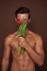 Wall Mural - Young macho man close face by tulips bunch