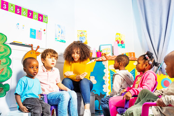 Wall Mural - Group of kids listen teacher to read a story book