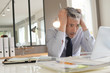 © goodluz - Stressed businessman working in contemporary office