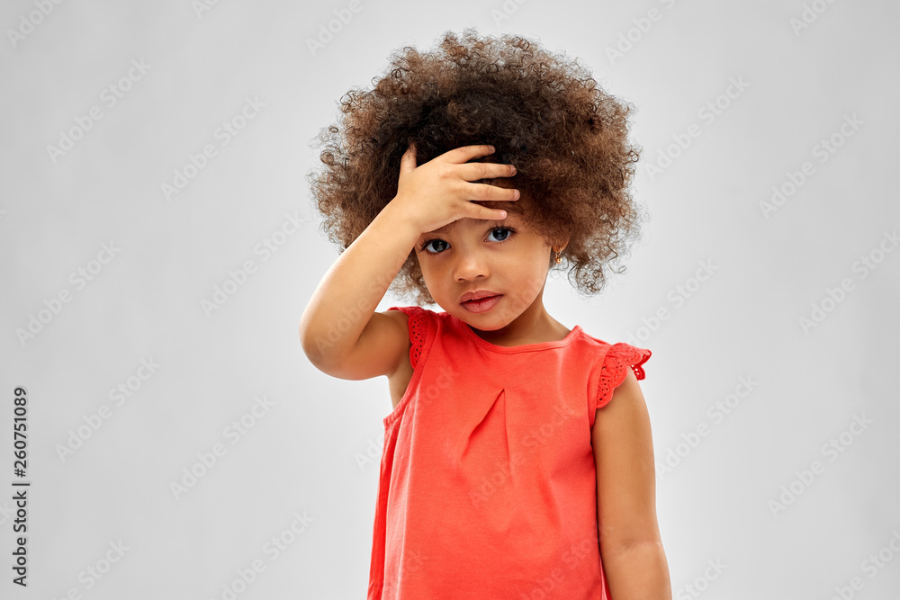 childhood and people concept - sad little african american girl touching her forehead over grey background - obrazy, fototapety, plakaty 