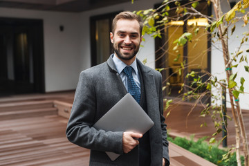 Wall Mural - Attractive young businessman wearing suit walking