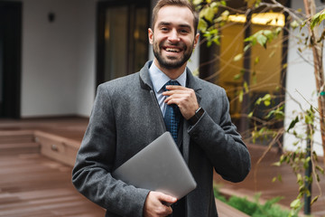 Wall Mural - Attractive young businessman wearing suit walking