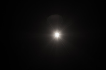 Wall Mural - white flash spark on black background. lens flare effect. defocused spotlight glow