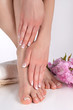 © Emilija - Girl legs with bare feet and hands with french manicure and pedicure on white towel in spa salon and decorative pink flower in background. Nails polish concept. Close up, selective focus