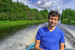 © Tatyana_Andreyeva - Handsome middle-aged man sitting at boat stern and floating along northern river on beautiful landscape background in summer sunny day. Travel concept. Chernaya river, Karelia, Russia