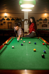 Wall Mural - Couple plays in billiard room, male player aiming