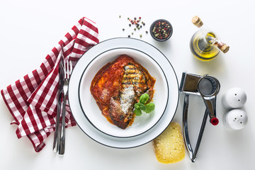 Wall Mural - Italian melanzane alla parmigiana dish, made of eggplants and tomatoes on a table, served in a plate. with cheese and basil. traditional cuisine