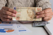 © Vergani Fotografia - Brazilian currency: Real. Person handling papernotes on desk. Retired woman holding bill on desk office.